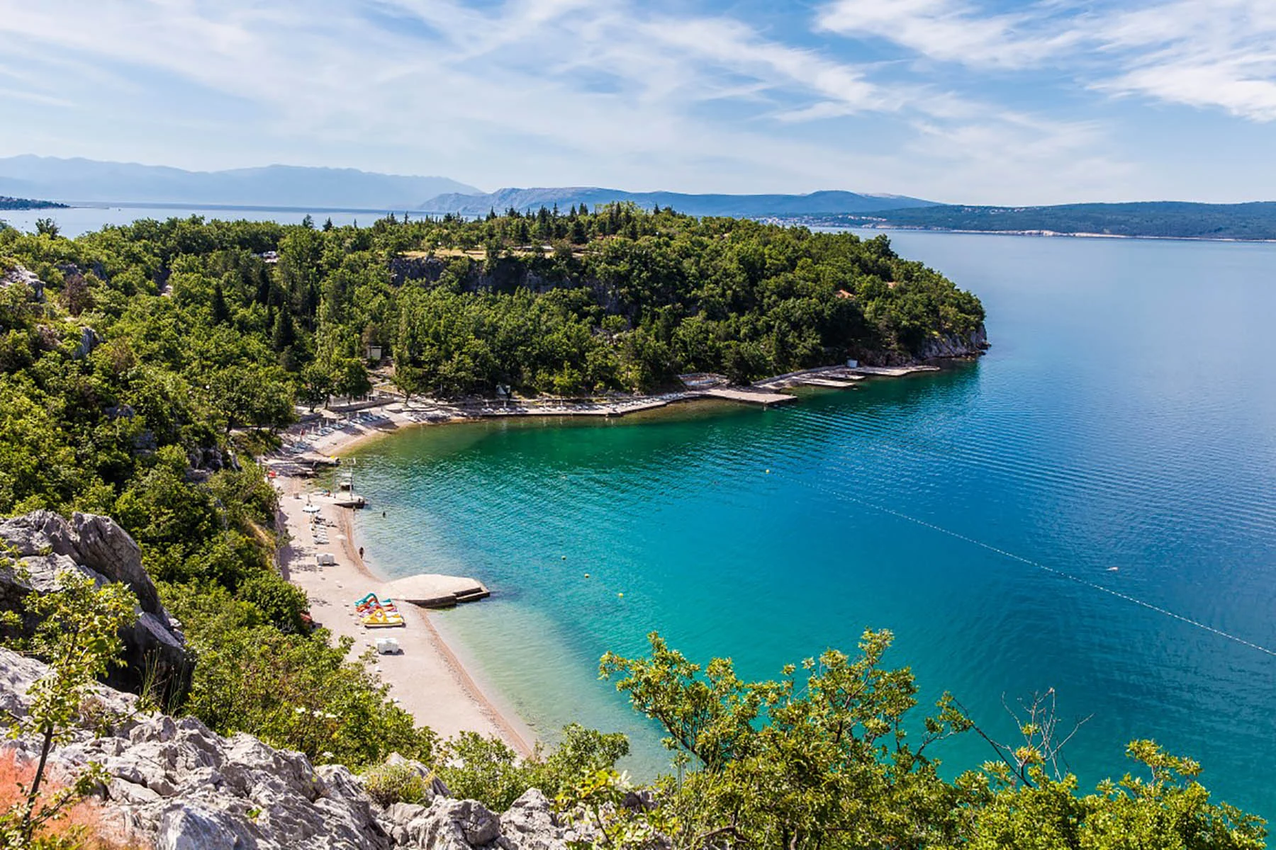 Photograph of a turquoise bay and pine trees on the Kačjak coast